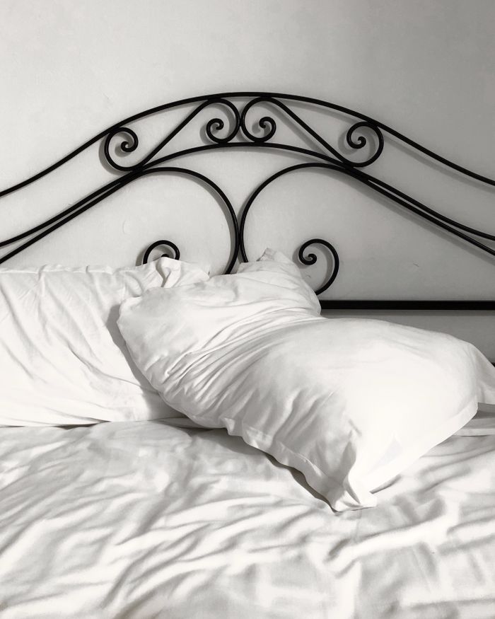 A close-up of a black iron headboard with white pillows and sheets, offering a cozy and inviting atmosphere.