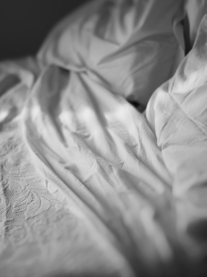 Close-up of crumpled white bedding with intricate textures in black and white.