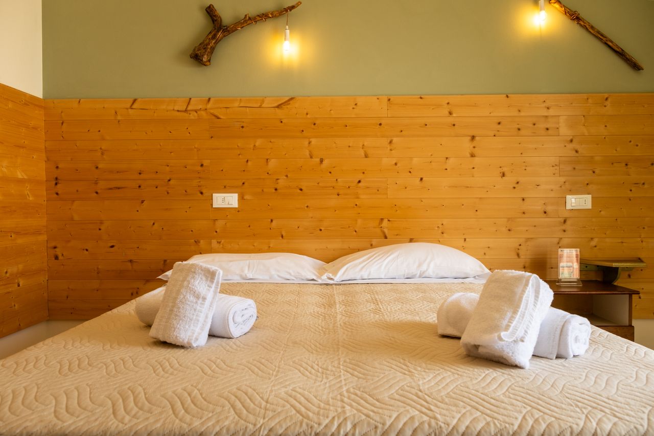 Warm wooden bedroom with a cozy design, featuring rolled towels and soft lighting.